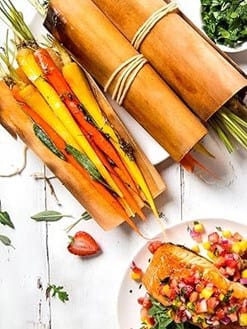 Colorful vegetable sticks wrapped in cedar leaf, ready for grilling or serving, showcasing sustainable, natural packaging.