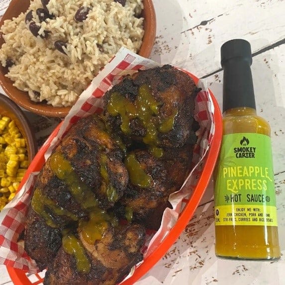 Crispy grilled chicken skewers with pineapple and smoky hot sauce, served with rice and corn, on a rustic wooden table.